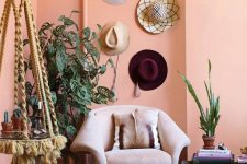 18 a peachy boho chic space with a burgundy printed rug, a suspended side table, a blush chair, potted plants and hats on the wall