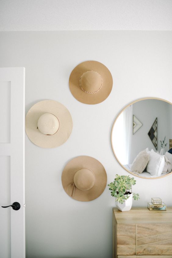 a small and lovely mini hat gallery wall of neutral hats is a cool idea for a mid-century modern or boho bedroom
