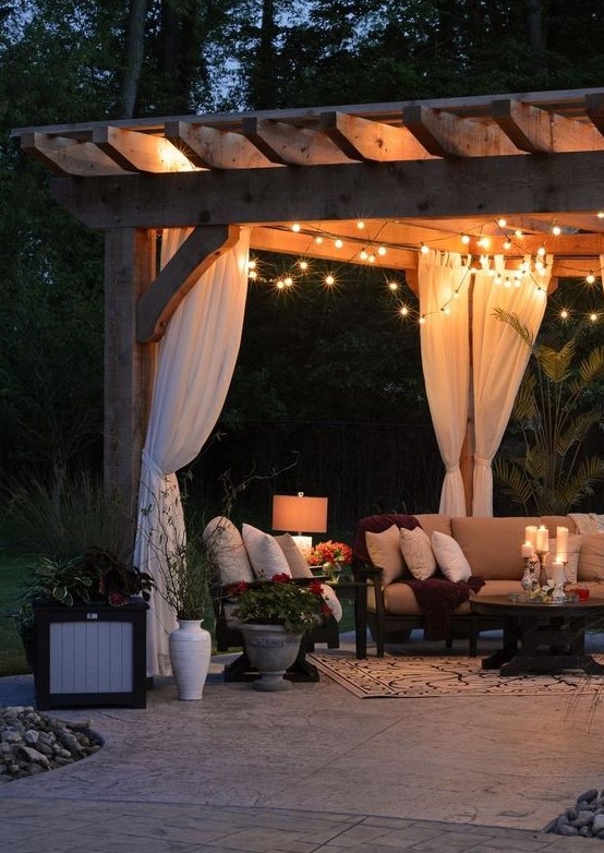 string lights, floor lamps and candles on the table make this outdoor living room very welcoming and very chic
