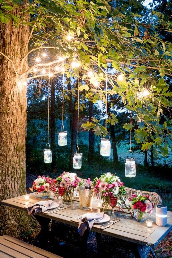string lights on the branches and pendant jar lanterns over the table plus candles on the table is very welcoming