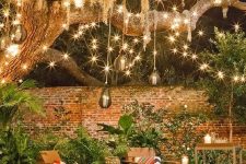 28 a backyard space with lots of string lights, rattan pendant lamps and candle lanterns all over the space is very cool