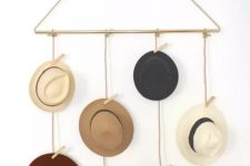 33 a pretty and simple hat holder of rope and a gold tube, with hats hanging on the rope and clothes pins is an easy piece that can be DIYed
