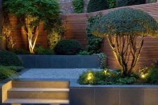 33 a stylish minimalist backyard with built-in lights and lit up trees that are highlighted with these lights