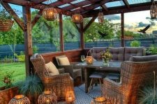 34 a terrace under a roof, with wicker and wooden furniture, greenery and lots of candles lanterns for lights