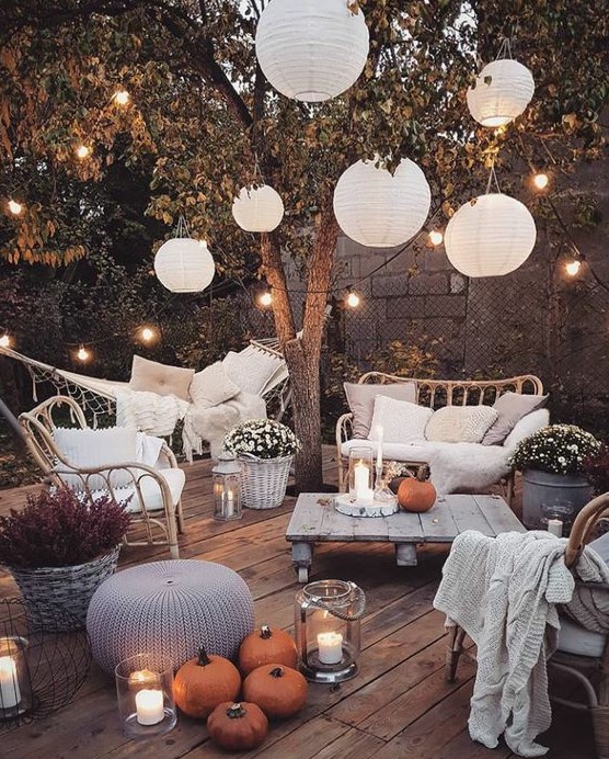 a welcoming backyard with candle lanterns, string lights over the space and paper lamps is amazing and cozy