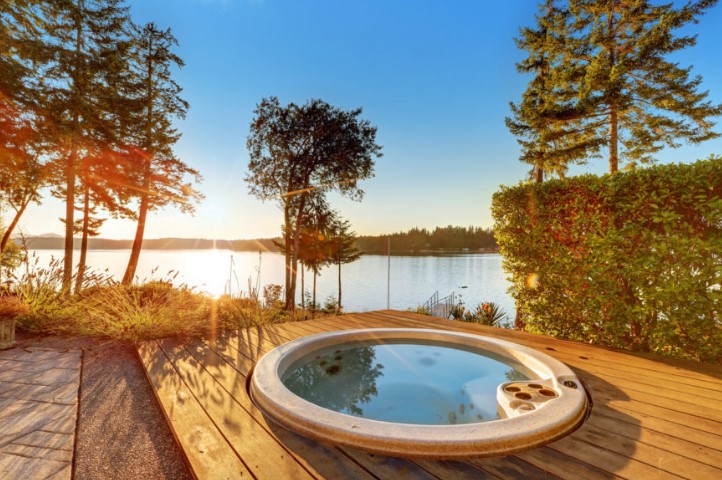 Small round tub fixed on a wooden plank deck with a spectacular view of the beach and a crystal clear view of the sunset