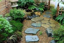 a beautiful Japanese garden at the entrance,w ith rocks as steps, potted greenery, a stone lantern and some trees and leaves