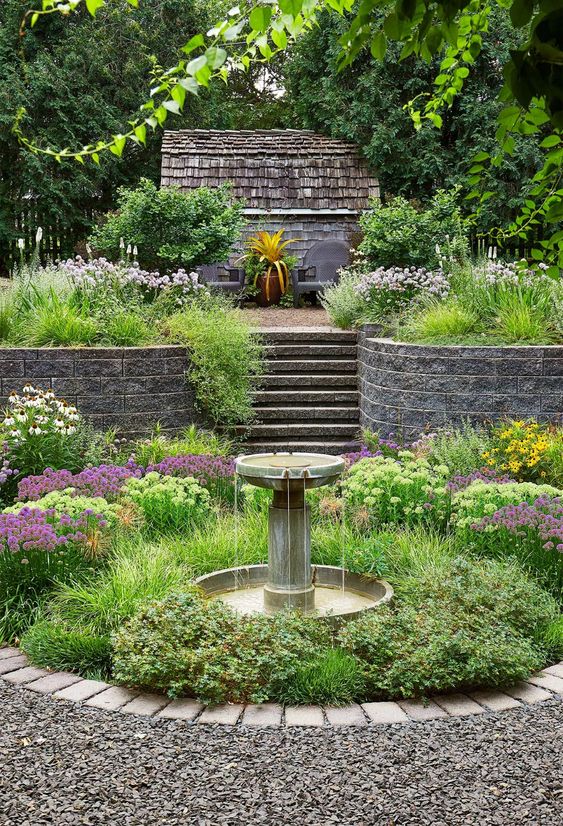 a beautiful and chic garden with lots of greenery and bold blooms, with a tiered fountain is a lovely space