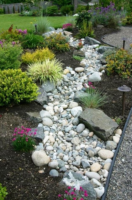a beautiful and low maintenance garden incorporating a river rock dry stream with herbs and blooms around