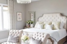 a beautiful and sophisticated greige bedroom with creamy upholstered furniture, neutral pillows, pritned curtains and a rug, a pendant lamp with crystals and mirrors
