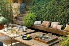 a beautiful and welcoming sunken terrace with greenery, built-in benches and low tables plus poufs is an amazing outdoor space