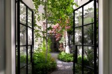 a beautiful and welcoming townhouse courtyard with greenery and some trees plus a stone floor is a lovely space to breathe in some air