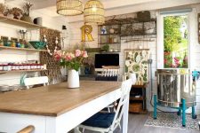 a boho farmhouse she shed with a dining table and chairs, open shelves, a TV, some wire shelves and cage pendant lamps