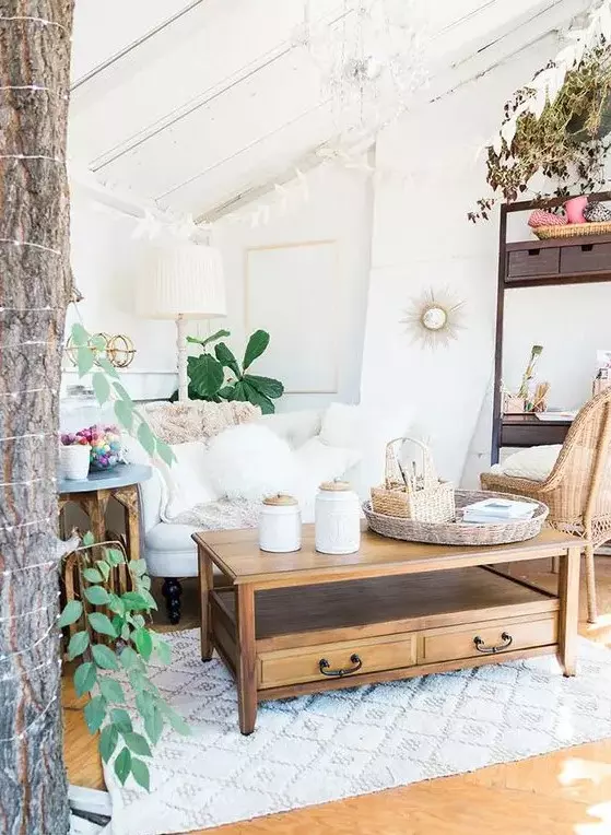 a boho living room in white with natural wood touches, a refined chandelier and potted plants