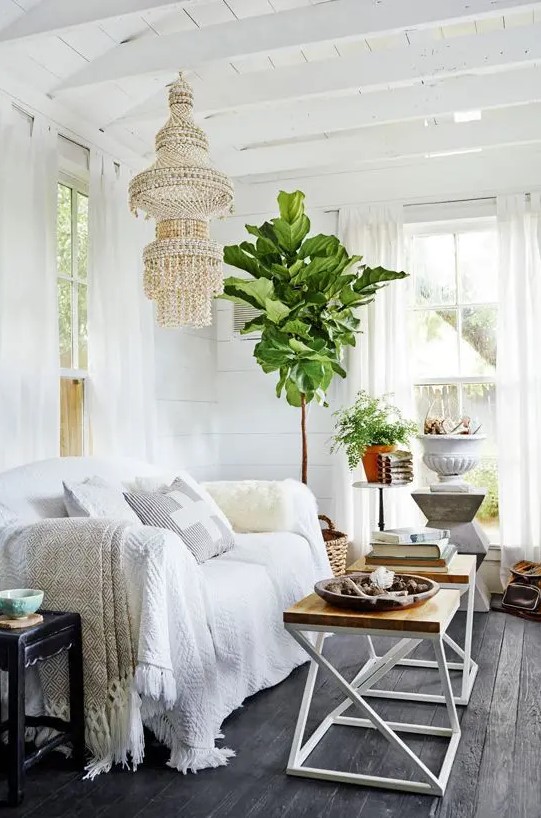 a boho living room she shed with a unique chandelier and potted plants looks super inviting