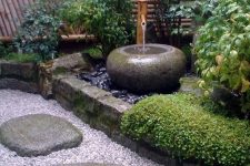 a chic front yard garden with gravel and large rock steps, greenery and plants and a traditional bamboo fountain plus a lantern