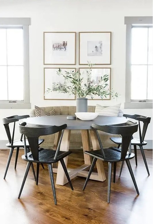 a chic modern farmhouse dining nook with a loveseat, a round table, black chairs, a chic gallery wall and greenery in a vase