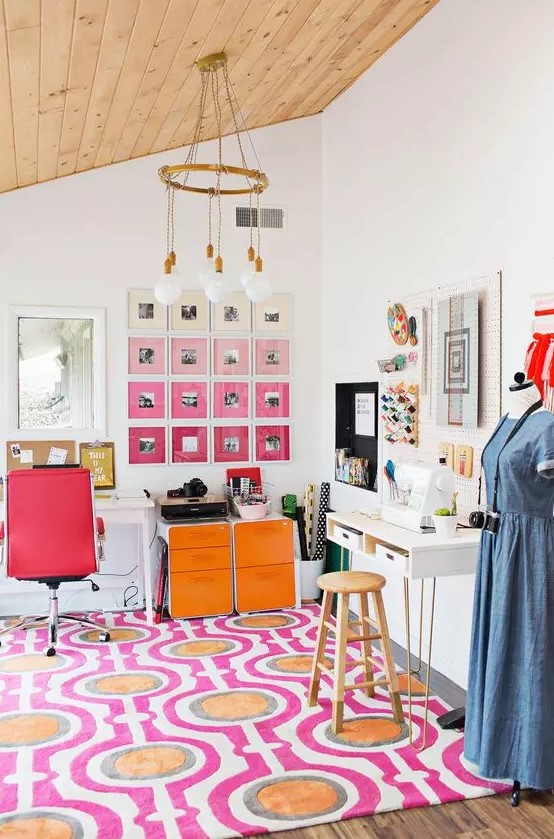 a colorful home office with a bold printed rug, a red leather chair, orange storage cabinets, an ombre pink gallery wall is a lovely space to be in