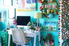 a colorful maximalist home office with a turquoise accent wall, a white desk, a green cabinet and lots of artworks and textiles in bold shades