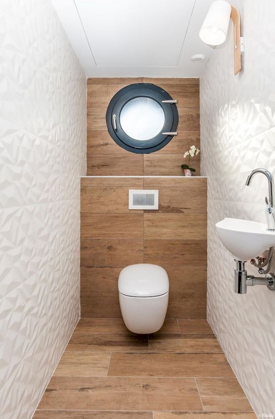 a contemporary powder room with wood-inspired tiles, geometric white ones, a window, a wall-mounted sink