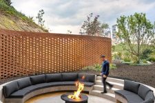 a contemporary round sunken patio around a fire pit, with built-in benches with black upholstery is an ultimate space to spend time in