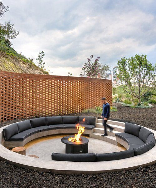 a contemporary round sunken patio around a fire pit, with built-in benches with black upholstery is an ultimate space to spend time in