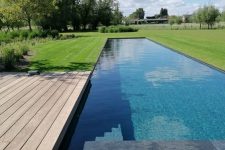 a contemporary space with green lawn and an infinity pool, a wooden deck and a lovely view of trees and greens is amazing