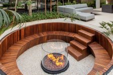 a contemporary sunken fire pit with a built-in stained bench and steps plus a fire pit in the center clad with glass