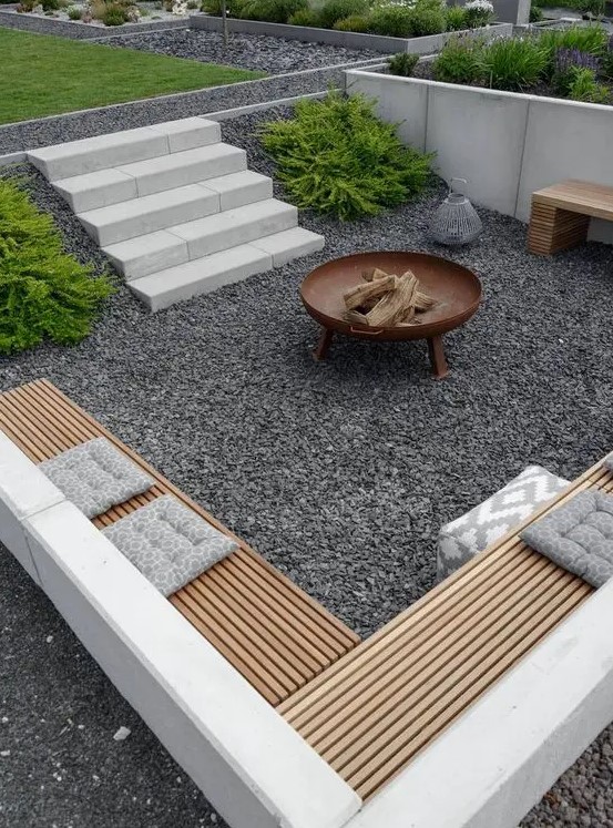a contemporary sunken patio with gravel on the ground, built-in benches and a fire pit is amazing for spending nights here