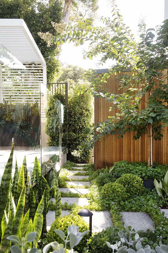 a contemporary townhouse garden with stone tiles, greenery, trees and a living wall plus some lights