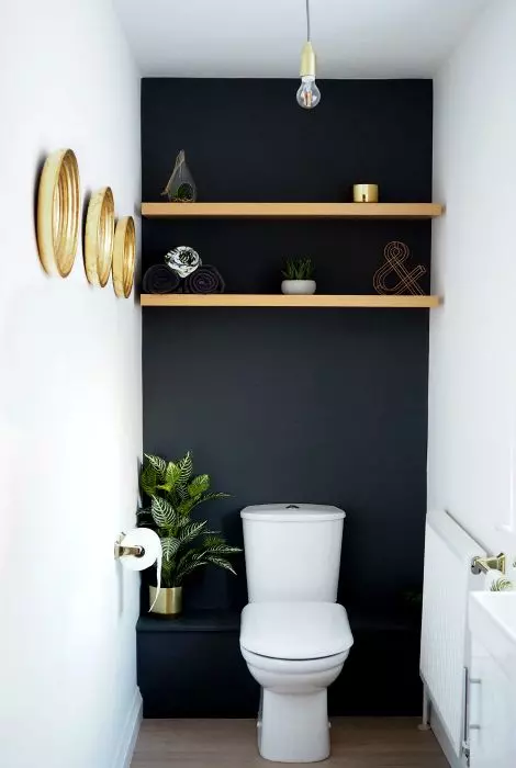 a cool modern powder room with a black accent wall, open shelves, a white vanity and a white toilet, a series of decorative plates