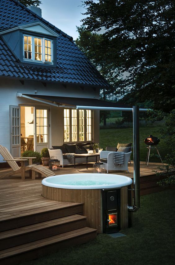 a cozy modern deck of wood, with steps, a bathtub, cozy modern neutral furniture and a roof over the space