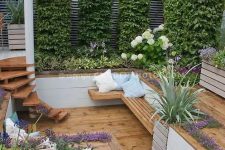 a creative sunken patio with living walls, greenery and blooms around, steps and a bench for sitting is a cool way to make use of a small space