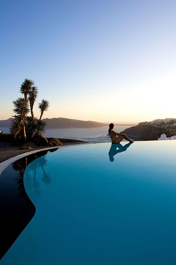 a curved infinity pool with a sea view and trees around is a gorgeous place to have a rest in and to enjoy the views