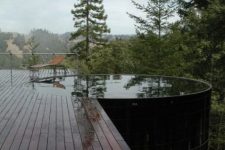 a dark stained wooden deck with a large and deep round pool that features amazing views of the nature around