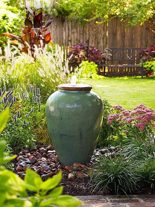 a delicate fountain of a planter is a unique idea for a zen garden, with blooms, greenery and rocks around