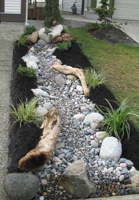 a dry stream style low water garden with rocks and pebbles, with grasses and driftwood is a great idea for an outdoor space