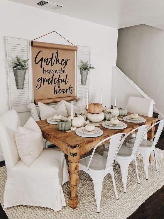 a fall modern farmhouse dining room with a sign, metal planters, a wooden table, metal and upholstered chairs