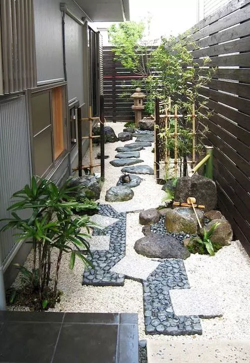 a fantastic Japanese garden with a catchy pathway, bamboo fances and greenery and a stone lantern in the corner of the garden