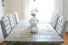 a farmhouse dining room with a shabby chic wooden table, blue upholstered chairs, a rustic chandelier and wicker shades