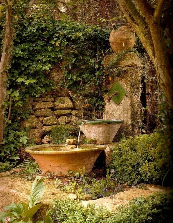 a flow of water fountain made of a faucet and some bowls and surrounded with greenery is a lovely solution