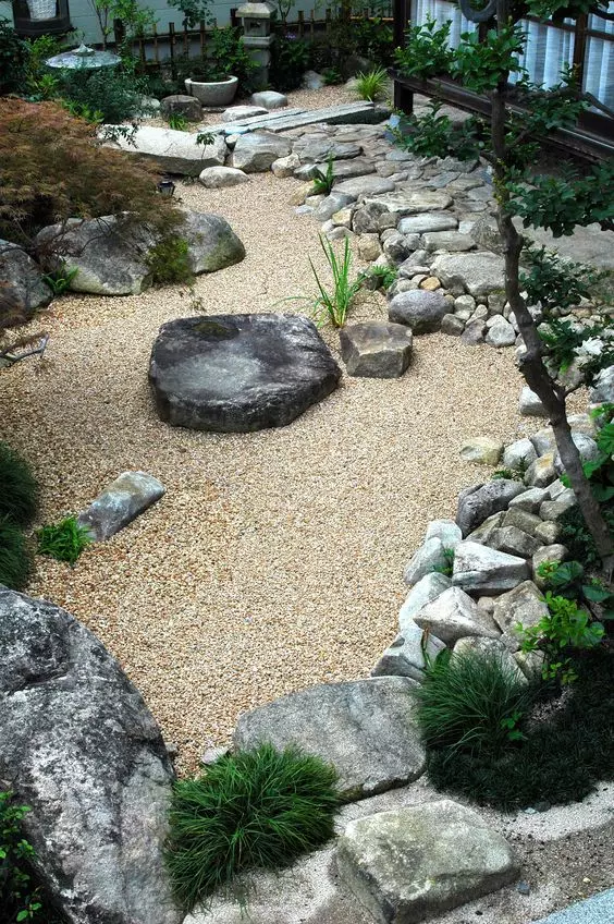 a gorgeous Japanese entrance garden with gravel, rocks and rock steps, some greenery, a water feature and a bit of trees