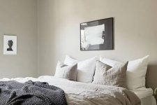 a greige bedroom with a large bed, lightweight nightstands, a beautiful pendant lamp and some lovely black and white artworks