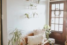 a greige boho entryway with a cane bench, potted plants, a wooden bead chandelier, wall-mounted clear planters with greenery