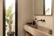 a greige contemporary bathroom with concrete walls and a floating sink, an open shelf and a black stool, a large mirror