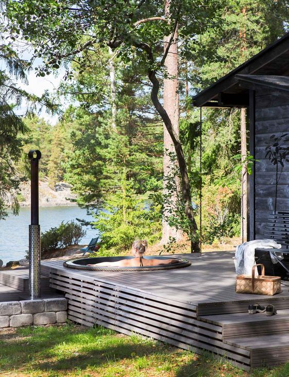 a grey Scandinavian deck with steps and a built-in bathtub with a gorgeous lake view is amazing for relaxation