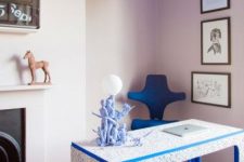 a jaw-dropping blush and electric blue home office with a vintage fireplace, a catchy terrazzo desk, a blue chair and a blue ceiling