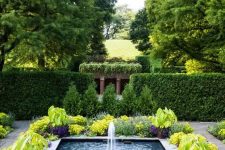 a large cool modern fountain surrounded with bold blooms and greenery is a fantastic idea for a modern outdoor space