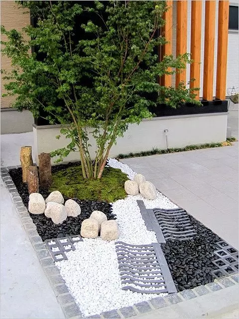 a lovely Japanese-inspired mini front yard garden with grass and a tree, rocks and pebbles is a cool idea for a contemporary space