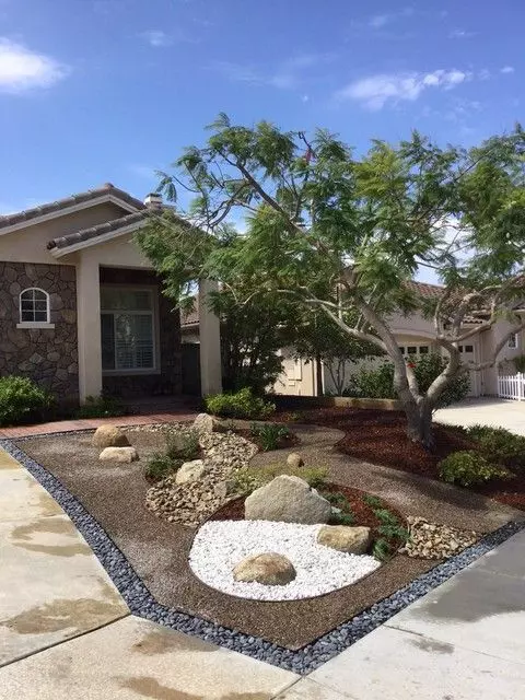 a lovely and simple Japanese-inspired front yard with gravel, stones and rocks and some greenery plus a large tree
